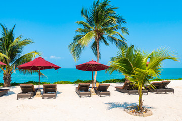 Beautiful tropical beach sea ocean with umbrella and chair around coconut palm tree on blue sky