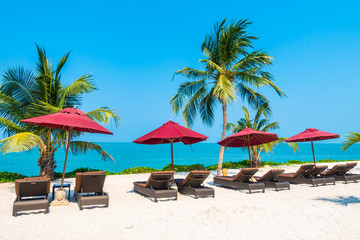 Obraz na płótnie Canvas Beautiful tropical beach sea ocean with umbrella and chair around coconut palm tree on blue sky