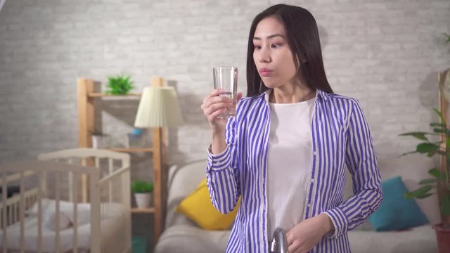 Positive young asian woman drinks clean fresh water