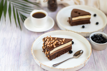 Holiday cake Three chocolates. Two white plates have two servings. On a light background. Birthday, holidays, sweets.