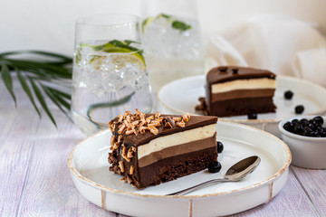 Holiday cake Three chocolates. Two white plates have two servings. On a light background. Birthday, holidays, sweets.