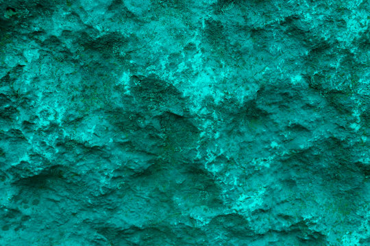 Texture of turquoise ragged rock. Background of turquoise rough uneven stone