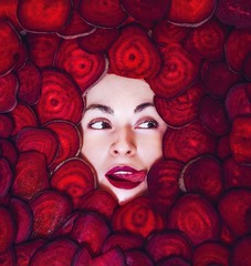 Woman's face with sticked out tongue between beetroot rings