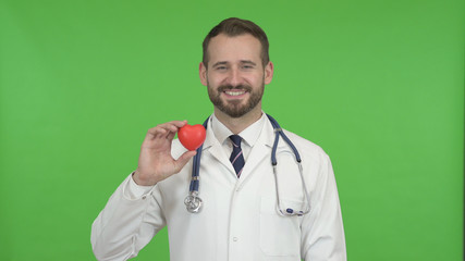 The Young Male Doctor Holding a Heart Shape and Smiling Against Chroma Key