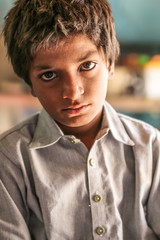 closeup of a poor staring hungry orphan boy in a refugee camp with sad expression on his face and his eyes are full of pain