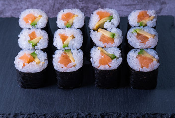 Salmon and avocado maki sushi on a slate. Japan food. Close up view.