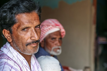Arab homeless father and son at a refugee camp with sad expression 