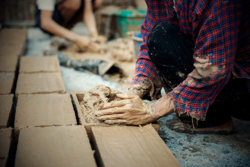 Hand of Worker making Brick block for building the house at construction site.