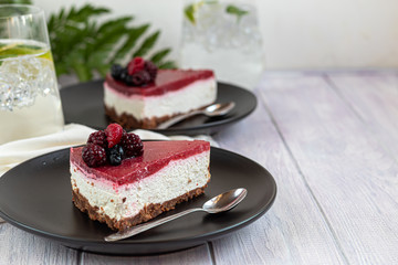 Cheesecake on two white plates, two servings. On a white background decorated with fresh berries. Birthday, holidays, sweets. I drink nearby.