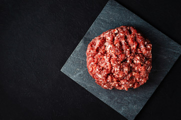 pile of fresh raw minced meat for cutlets on a black background.