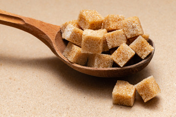 brown refined sugar in a wooden spoon on a craft paper background