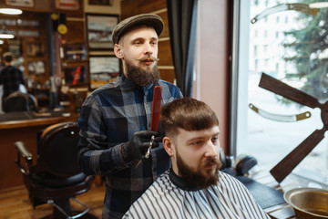 Barber holds comb and cuts the client 's hair
