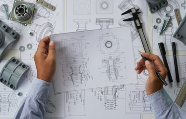 Engineer technician designing drawings mechanical parts engineering Engine.manufacturing factory Industry Industrial work project blueprints measuring bearings caliper tools