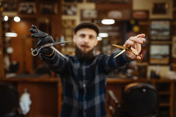 Fototapeta na wymiar Barber shows sciccors, retro style barbershop