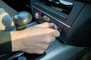 A man in a modern car. Hand switches the seat heating level.