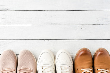 Overhead shot of different woman’s shoes on white wooden table with copyspace. Fashion background. Flat lay
