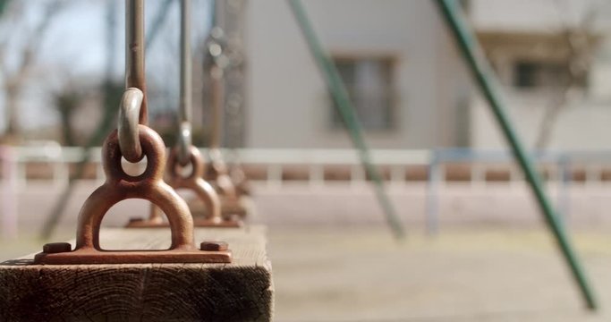 An old swing set swings slightly in an empty playground in Tokyo.