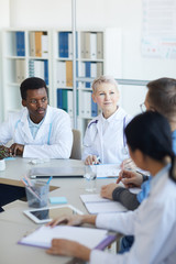 Multi ethnic group of doctors sitting at table during committee meeting at medical council