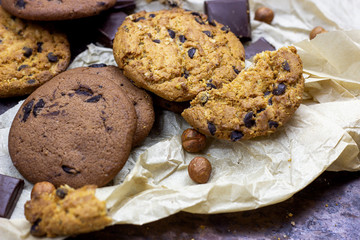 Freshly baked American chocolate chip cookies on rustic black metal table background.