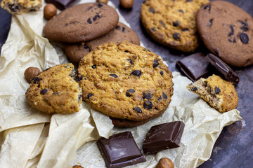Freshly baked American chocolate chip cookies on rustic black metal table background.