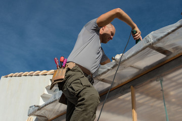 Construction worker repairing the roof of a house