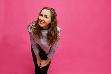 Stylish caucasian girl in a pale blue t-shirt looking flirting at the camera on a pink background.