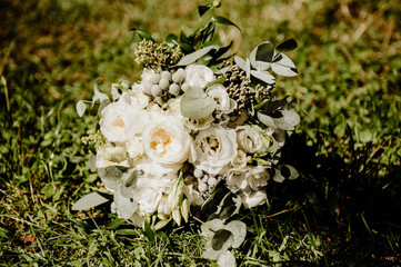 Obraz na płótnie Canvas a bouquet of white roses and peonies lies on the green grass