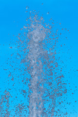 Water squirting from a fountain against a blue sky