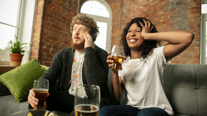 Beer. Excited couple, friends watching sport match, chsmpionship at home. Multiethnic friends, fans cheering for favourite national basketball, tennis, soccer, hockey team. Concept of emotions.