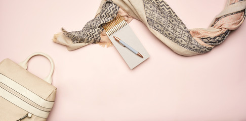 Bag and scarf with notebook on pink background