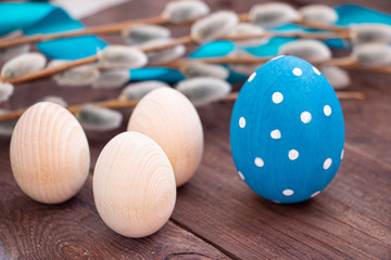 Easter holiday card. Classic blue painted egg and three natural-colored eggs close-up.