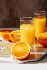Fototapeta na wymiar freshly squeezed orange juice in a glass, juicy cut oranges, sunny morning