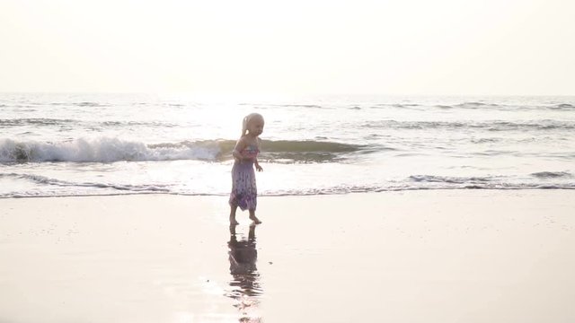 Girl child jumping and dancing on the sea beach. Slow motion