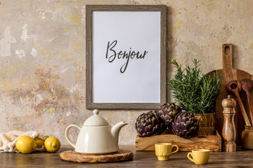 Stylish interior of kitchen space with wooden table, brown mock up photo frame, lemons, vegetables, tea pot, cups and kitchen accessories in wabi sabi concept of home decor. 