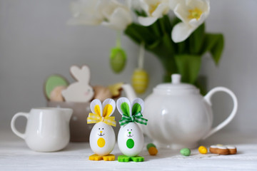 Easter table setting with bunnies, gingerbread, eggs and flowers. Happy Easter Greeting Card Template. Easter cake and colorful eggs on festive table. The concept of family celebration.