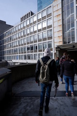 Man with a backpack walking down a catwalk Waterloo in a crowd 