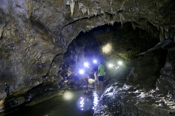 People in Cantabon cave with flash lights, standing water, Siquijor, Philippines