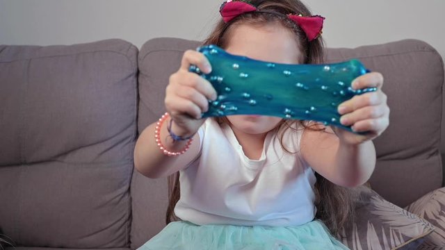  Baby girl having fun making ping slime. Child playing with hand made toy slime.Relax and Satisfaction. Oddly satisfying red slime for pure fun and stress relief.