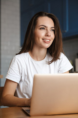 Happy woman indoors at home using laptop computer.