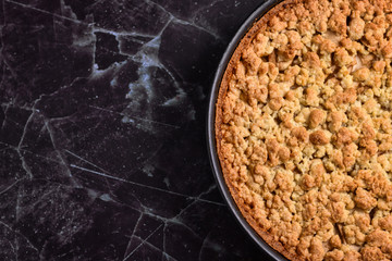 Top view of traditional European apple pie with topping crumbles in springform pan on right side...