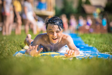 Summer camp. Szczęśliwy chłopak świetnie się bawi w wodzie podczas pobytu nakolonii, na obozie młodzieżowym latem nad morzem - obrazy, fototapety, plakaty