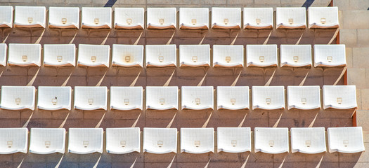 empty plastic seat on tribune of the stadium cast a shadow on the concrete