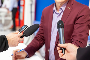 Media interview - journalists with microphones interviewing politician or business person
