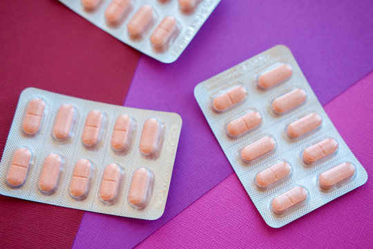 Heart pills. Medical tablets on pink background.