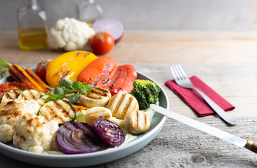 Fresh organic grilled vegetables bell pepper,mushrooms,broccoli,cauliflower,carrots seasoned with herbs on a round plate.