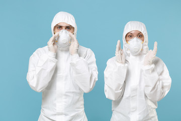 Two people in protective suits respirator masks isolated on blue background studio. Epidemic pandemic new rapidly spreading coronavirus 2019-ncov originating in Wuhan China, medicine flu virus concept