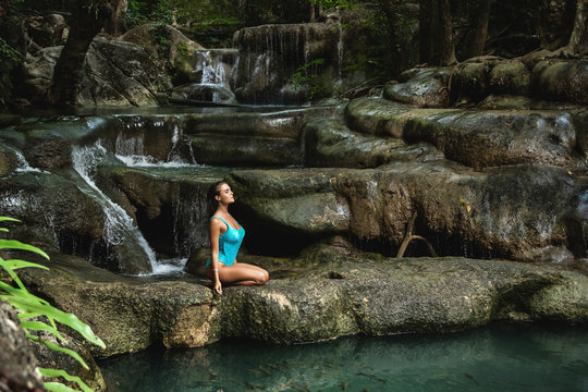 Young and sexy woman on the beautiful waterfall in the jungle