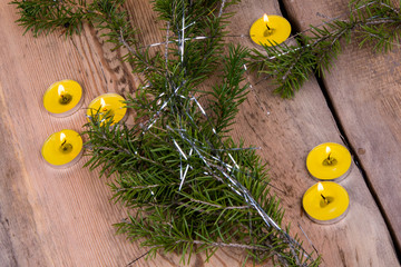 New Year card with Christmas greetings with your text and Christmas decoration from a tree twig, a lit candle, on a wooden light background