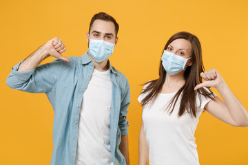 Two people in sterile face masks white t-shirts isolated on yellow background studio. Epidemic...