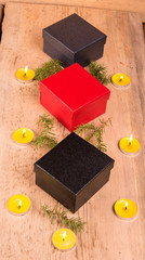 Christmas card, three boxes, candles, sprigs of Christmas tree on a wooden background